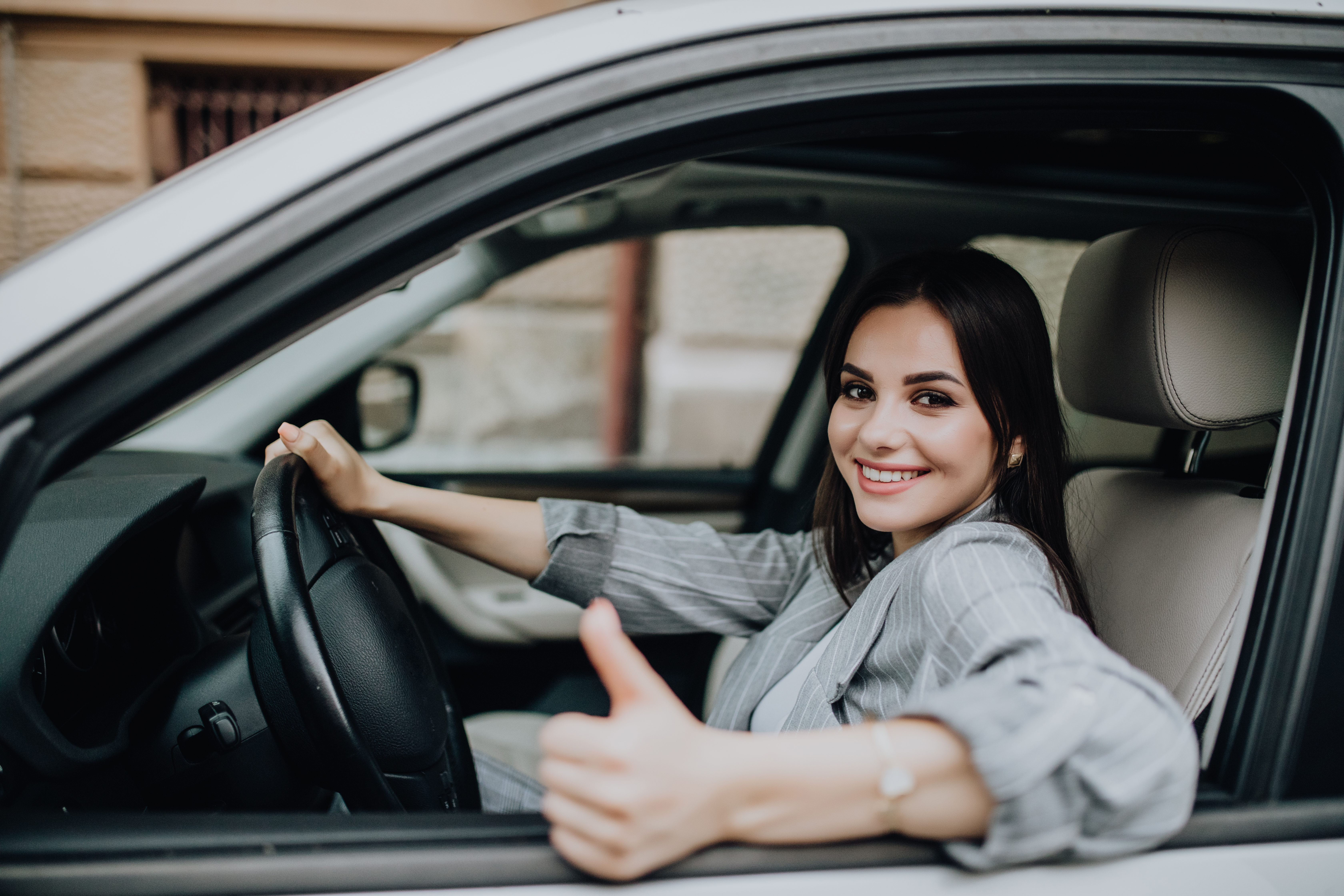 young-woman-sitting-car-showing-thumbs-up